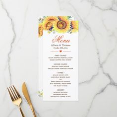 a menu card with sunflowers on it next to a gold fork and knife