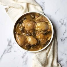 a bowl filled with chicken and mushrooms on top of a white tablecloth next to a napkin