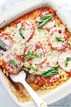 a casserole dish with tomatoes, spinach and mozzarella on top