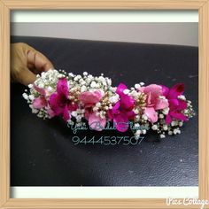 pink and white flowers are placed on top of a black leather surface in a wooden frame