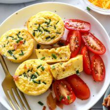 an omelet with tomatoes and cheese on a plate next to other food items