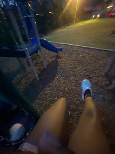 someone is sitting on the ground with their feet propped up in front of a playground