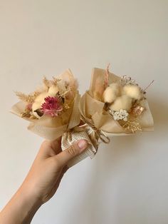 two small bouquets with flowers are held in someone's hand