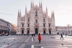 a woman in a red dress is walking towards a cathedral