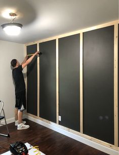 a man is painting the walls in an empty room with black paint and wood paneling