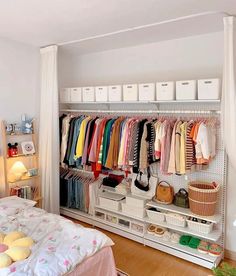 an organized closet with clothes and baskets on the shelves, next to a bed in a bedroom