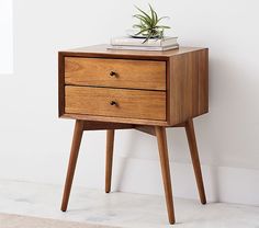 a small wooden table with two drawers and a plant on top