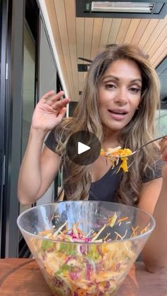 a woman holding a spoon over a bowl of food