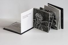 an open book with black and white drawings on it's cover, sitting on a table