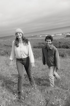 black and white photograph of two people walking in a field with one person wearing a hat