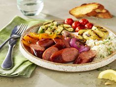 a plate filled with sausage, rice and vegetables