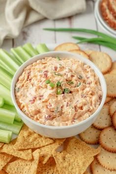 a bowl of dip surrounded by crackers and celery