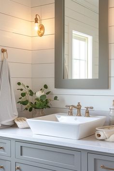 a bathroom sink sitting under a mirror next to a white counter top with towels on it