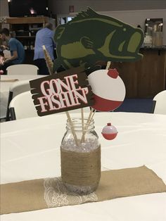 there is a fish sign in a jar on top of a table with paper decorations