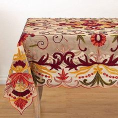 a table covered with a multicolored floral design on top of a hard wood floor