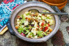 a bowl filled with apples and raisins on top of a table next to a spoon