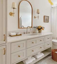 a bathroom with white cabinets and gold accents