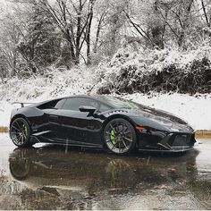 a black sports car parked on the side of a road in front of snow covered trees