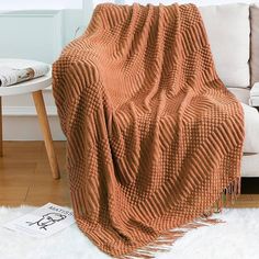 an orange blanket sitting on top of a white rug