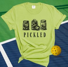 a t - shirt with the words pickled on it next to a yellow ball