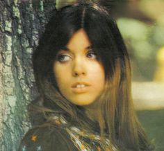 a young woman standing next to a tree