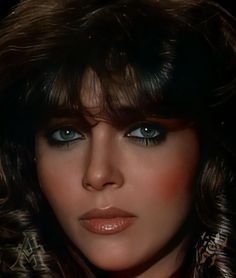 a close up of a person with long hair and blue eyes wearing a fur coat