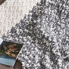 a book is laying on top of a gray and white blanket