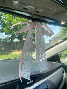 a pink ribbon tied to the back of a car's dash board with lace on it