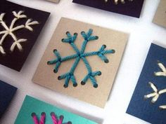 several snowflakes made out of yarn are displayed on a table with other cards