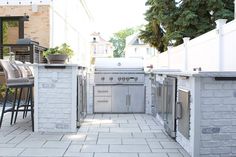 an outdoor kitchen with grill and bar stools