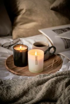 two candles are sitting on a wooden tray