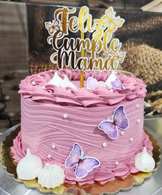 a cake with pink frosting and butterflies on top that says felize cumple mama