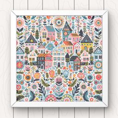 an art print with colorful houses and flowers on the front, against a wooden wall