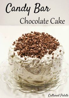 a cake with white frosting and chocolate shavings on top is sitting on a glass plate