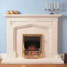 a fire place with candles on the mantle and blue walls in the room behind it