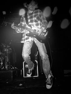 a man standing on top of a stage holding a guitar