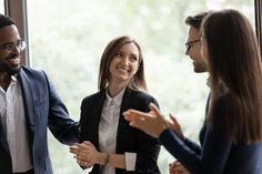 three business people having a conversation in front of a window with their hands out to each other