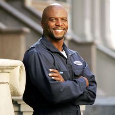 a man standing in front of a building with his arms crossed and smiling at the camera