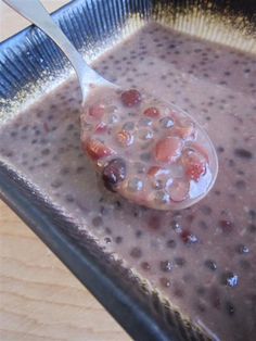 a spoon with some food on it in a bowl next to a cup filled with liquid