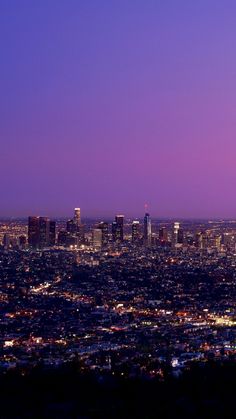 the city lights are lit up at night in this view from atop a hill with no people