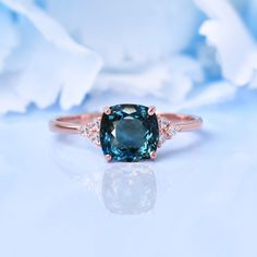 a blue diamond ring with two diamonds around it on top of a white flower background