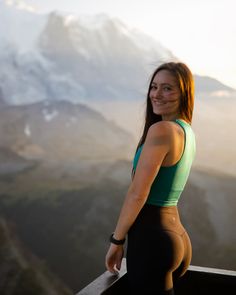 a woman standing on top of a mountain with her back turned to the camera and smiling