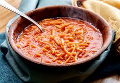 a wooden bowl filled with pasta on top of a table