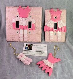 two light switch covers with pink and white designs on them, one is attached to a chain