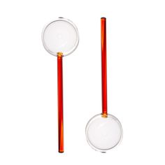 two orange and clear glass objects with red handles on white background, side by side