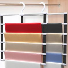 several colors of fabric hanging on a rack in front of a closet with metal rails