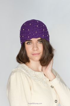 a woman is wearing a purple hat and posing for the camera with her hand on her chin