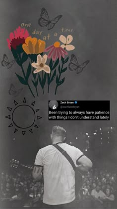 a man holding a guitar standing in front of a wall with flowers and butterflies on it