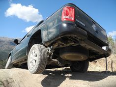 a black truck is parked on the side of a dirt road