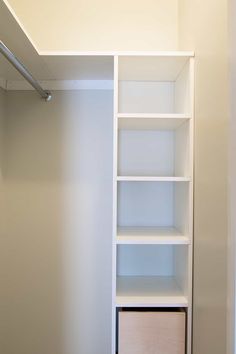 an empty closet with white shelves and drawers